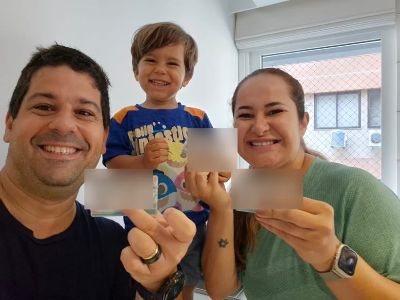 Casal com o filho pequeno comemorando a residência permanente