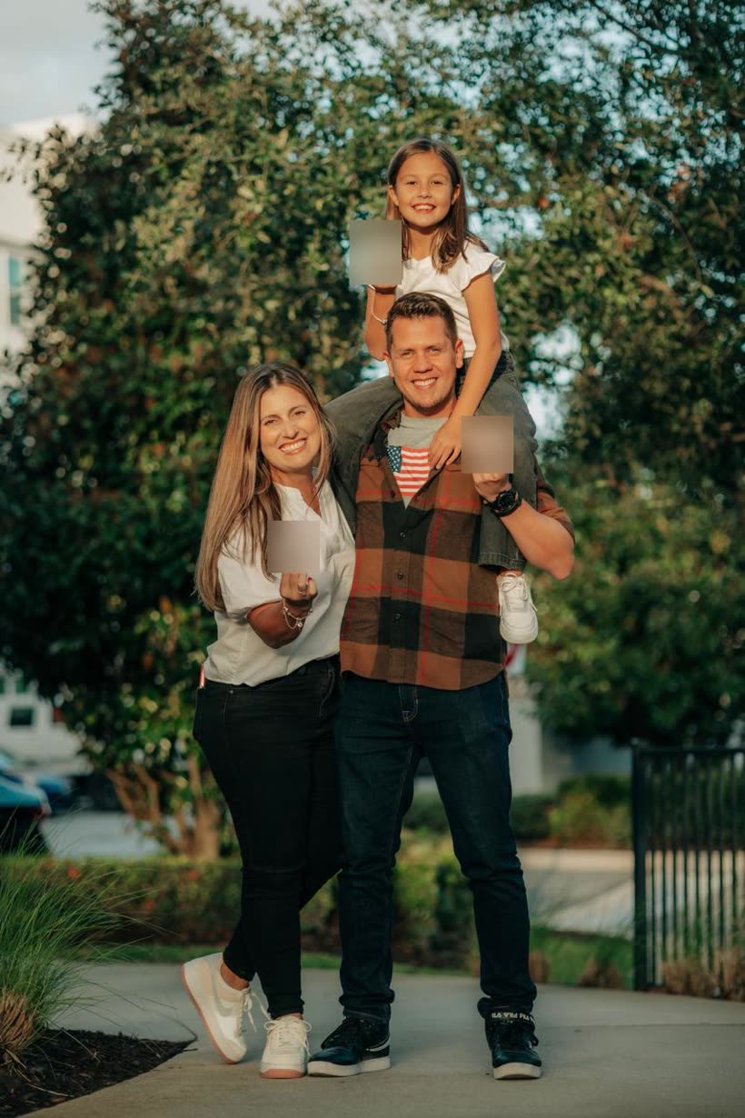 Casal ao ar livre com a filha nos ombros, celebrando a aprovação